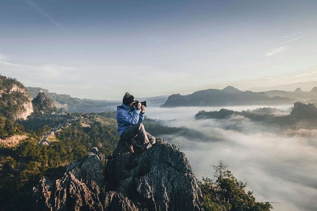 man on top of mountain taking pictures